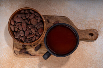 Ceremonial Cacao drink. Hot ceremonial chocolate in black cup with cocoa beans. Woman hands holding cocoa mug. Organic healthy chocolate drink prepared from beans, without creamer, sugar or toppings