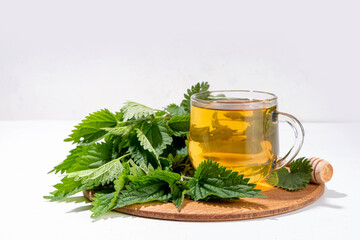 Nettle Tea hot plant drink in transparent glass cup. Organic natural herbal tea without caffeine,...