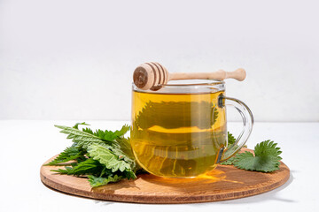 Nettle Tea hot plant drink in transparent glass cup. Organic natural herbal tea without caffeine,...