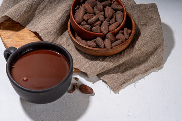 Ceremonial Cacao drink. Hot ceremonial chocolate in black cup with cocoa beans. Woman hands holding cocoa mug. Organic healthy chocolate drink prepared from beans, without creamer, sugar or toppings - 785295953