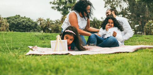 Happy indian family having fun painting with children and doing picnic outdoor at city park - Spring lifestyle - Focus on mother face