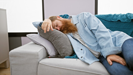Exhausted young irish man with redhead beard finds comfort relaxing on cozy sofa, deeply sleeping...