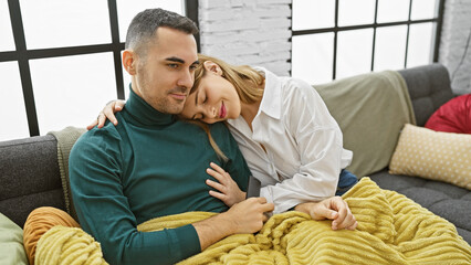 A loving couple cuddles on a sofa in a cozy living room, portraying a warm emotional bond.