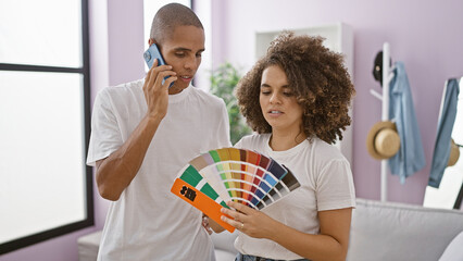 Beautiful couple immersed in a serious talk over a phone choosing the perfect paint color for their...