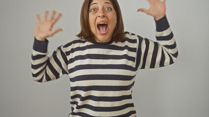 A joyful middle-aged hispanic woman in a striped sweater expresses excitement against a white...