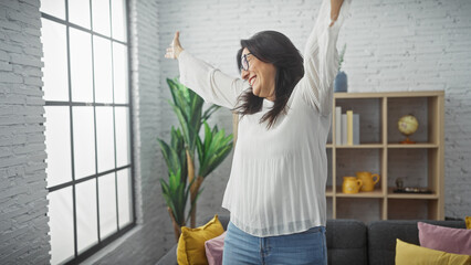 Mature hispanic woman feeling joyful in a bright modern living room setting