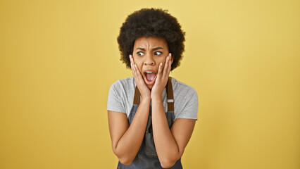 A shocked african american woman with curly hair stands against a yellow background, portraying a...
