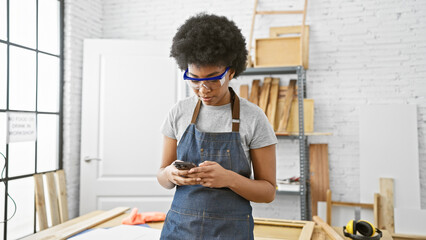 African american woman using smartphone in carpentry workshop