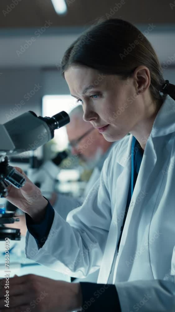 Poster vertical screen: female bioengineer looking at dna samples under a microscope in a modern applied sc