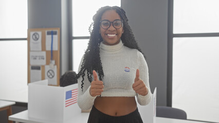 A cheerful woman with glasses giving thumbs up in a polling station with us flags during an...