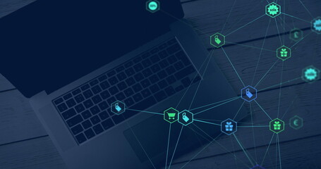 Image of web of connections with icons floating over a laptop computer lying on a wooden table