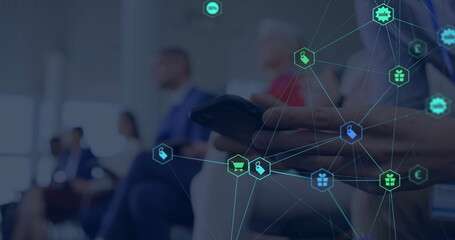 Image of web of connections with icons floating over hands of a man using a smartphone