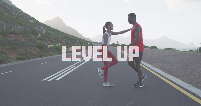 Fototapeta Image of the words level up written in white over couple exercising on mountain road