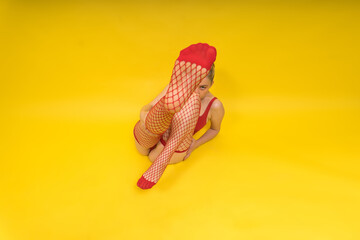 Woman in red fishnet stockings posed on yellow background