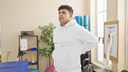 Handsome man with back pain standing in a physiotherapy clinic room