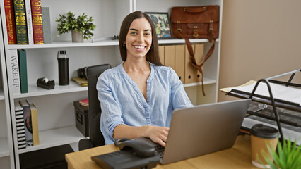 Confident young hispanic woman enjoys success as she works at office, beautiful business...