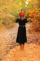 Young witch with jack o lantern in forest