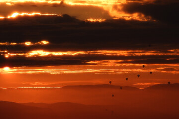 hot air balloons flying among clouds at sunrise