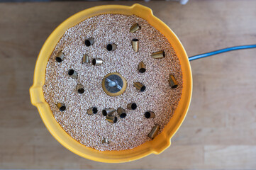 Vertical view of a vibrating tumbler with walnut shell grain cleaning the 9mm pods for reloading