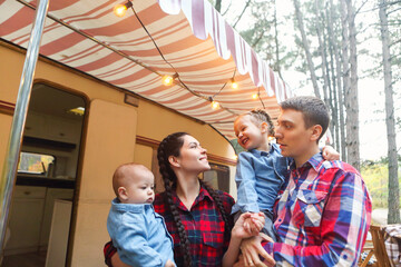 Portrait of a young smiling family while hugging near house on wheels