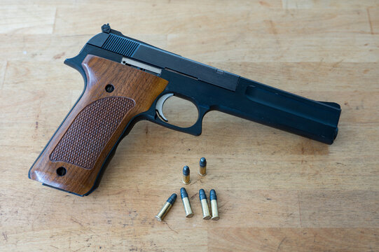 A nice classic .22 caliber pistol and a few standard bullets on the wooden table