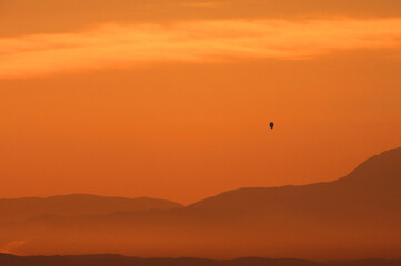 hot air balloons flying among clouds at sunrise