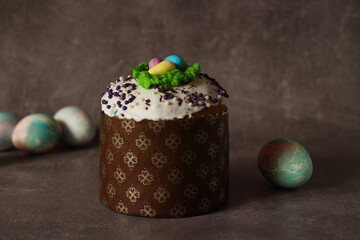 Easter cupcake with white icing and colorful eggs on dark background