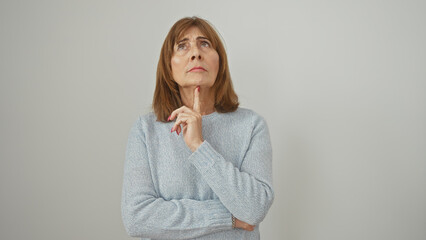 A contemplative senior woman with short hair stands against a white background, evoking...
