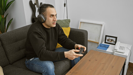 A focused hispanic man enjoying video games in a cozy living room setting