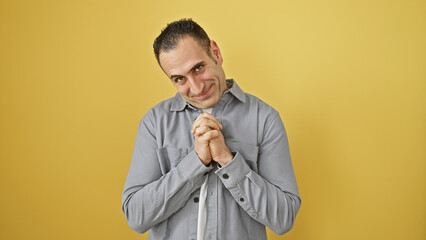 Hispanic man in button-up shirt smiling and gesturing against a yellow isolated background