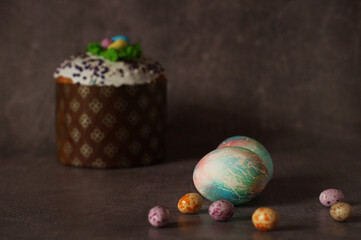 Easter colorful chicken eggs on dark background with Easter cupcake