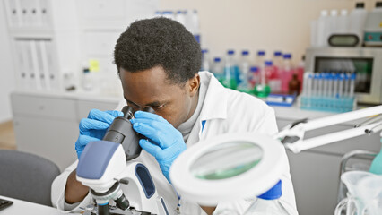 African male scientist using microscope in laboratory