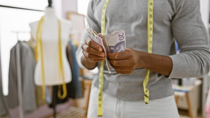 Adult black man counts swedish krona in a tailor shop, indicating profession, finance, and entrepreneurship - obrazy, fototapety, plakaty