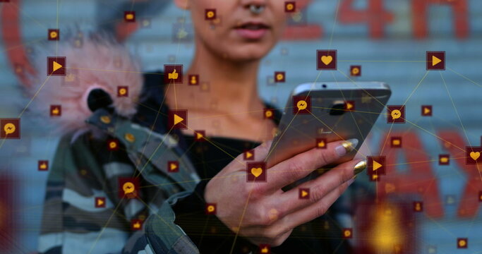 Image of globe of digital icons over biracial woman using smartphone outdoors - Powered by Adobe
