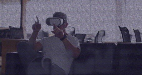 Image of vhs glitch effect over caucasian man wearing vr headset at office