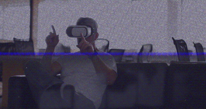 Image of vhs glitch effect over caucasian man wearing vr headset at office - Powered by Adobe