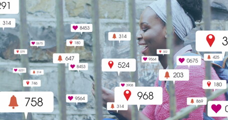 Image of multiple social media icons over african american woman using smartphone outdoors