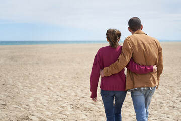 Couple walking in beach sand to the sea