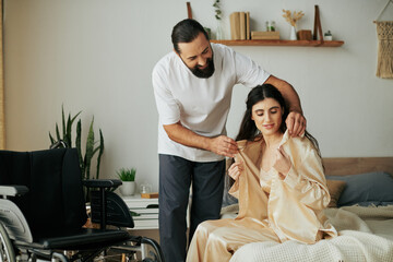 cheerful loving man in homewear helping his disabled wife to change into pajama in bedroom at home