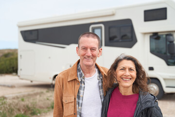 Mature couple smiles to the camera by thier new van