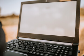 Valmiera, Latvia - August 17, 2024 - Close-up of an open laptop with a blank screen, set against an outdoor, blurred background.