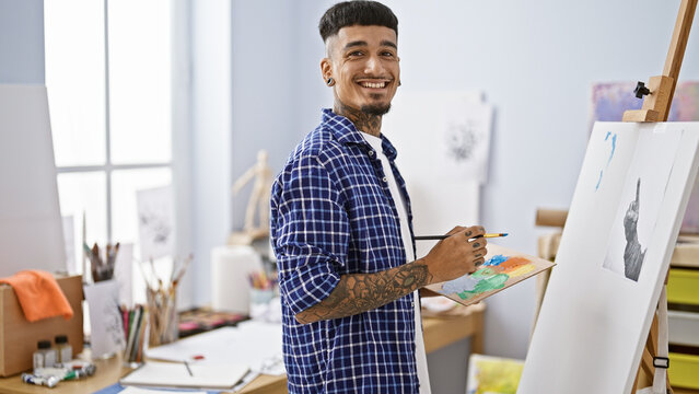 Confident young latin man artist delighting in drawing indoor at his art studio, creatively smiling