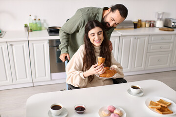 joyous man having great time at breakfast with his beautiful disabled wife that eating croissant