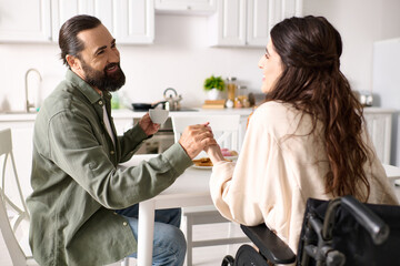 attractive jolly woman with disability in wheelchair enjoying breakfast with her bearded husband