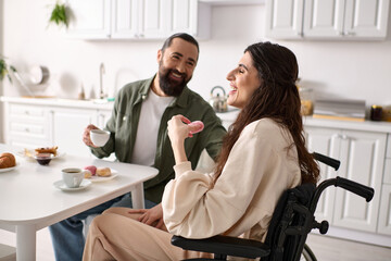 merry woman with inclusivity in wheelchair eating sweets at breakfast with her handsome husband