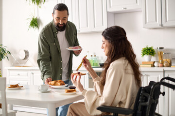 happy attractive woman with disability in wheelchair eating breakfast with her loving husband