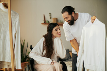 bearded caring man helping his inclusive wife on wheelchair to get dressed while in bedroom - obrazy, fototapety, plakaty