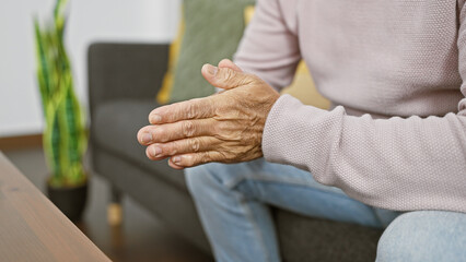 Close-up of a mature man's hands indoors, portraying senior life in a comfortable home setting.