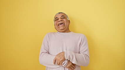 Laughing middle-aged man with grey hair against a yellow isolated background.