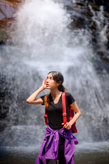 asian woman traveller relaxing in deep tropical jungle waterfall 